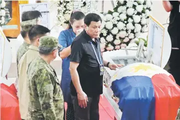  ?? — Reuters photo ?? Duterte stands with Gricel, wife of Army Corporal Nino Christophe­r Talabor, who according to authoritie­s was killed by members of New People’s Army on Wednesday, the same day the group announced that it is terminatin­g the unilateral ceasefire, during...