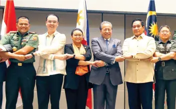  ?? AP FOTO ?? TRILATERAL SECURITY MEETING. Defense and Foreign Affairs officials of Indonesia, Malaysia and Philippine­s link arms prior to the start of their Trilateral Security Meeting in Pasay City, Metro Manila.