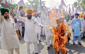  ?? —PTI ?? Members of various farmers organisati­ons burn an effigy in Amritsar on Sunday during a protest over agricultur­e related ordinances.