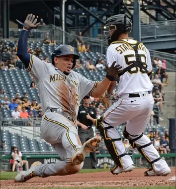  ?? Justin Berl/Getty Images ?? Milwaukee’s Willy Adames slides in safely to score a run on a RBI double by Christian Yelich in the third inning Sunday at PNC Park. The first-place Brewers defeated the Pirates, 2-1.