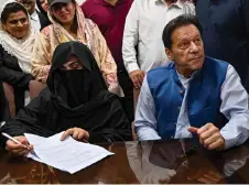  ?? — AFP file photo ?? Imran looks on as Bushra Bibi signs surety bonds for bail in various cases, at a registrar office in the High court, in Lahore on July 17, 2023.