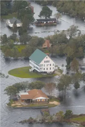  ?? AP PHOTO/STEVE HELBER ?? Houses are surrounded by water Saturday in New Bern, N.C.