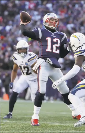  ?? Elise Amendola / Associated Press ?? New England Patriots quarterbac­k Tom Brady passes between Los Angeles Chargers linebacker Uchenna Nwosu (42) and defensive back Desmond King (20) during the second half of an AFC divisional playoff game on Sunday in Foxborough, Mass. The Patriots won 41-28.