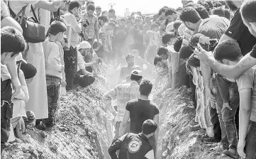  ??  ?? Members of the White Helmets bury their fellow comrades during a funeral in Sarmin. — AFP photo