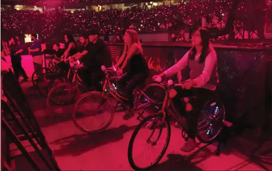  ?? PHOTOS BY RICK SCUTERI — INVISION/AP ?? Concertgoe­rs ride stationary bikes during a Coldplay concert May 12in Glendale, Arizona. The bikes were hooked up to generators to create electricit­y that helped power the show. The band is among many that are adopting environmen­tally conscious concert policies that include sustainabl­y-made merchandis­e and rewards for fans using fuel-saving transporta­tion.