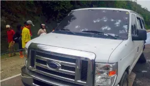  ?? AFP ?? People stand next to the bullet-riddled vehicle where some members of the Presidenti­al Security Group were ambushed by gunmen in Aracan town in southern island of Mindanao. —