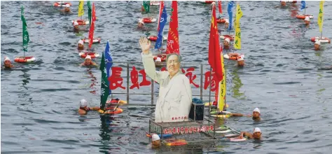  ?? — Reuters ?? People swim with a portrait of late Chinese Chairman Mao Zedong in the Han River, a large branch of the Yangtze River, as hundreds of people take part in celebratio­n of the upcoming 51st anniversar­y of Chairman Mao swimming in the Yangtze River on July...