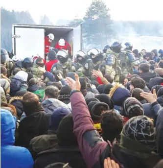  ?? RAMIL NASIBULIN/BELTA POOL PHOTO VIA AP ?? Belarusian servicemen try to keep order while migrants get humanitari­an aid at the Belarus-Poland border near Grodno, Belarus, on Friday.