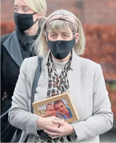  ??  ?? Jane Midgley, mother of victim Simon Midgley, carries a photograph of him and second fire victim Richard Dyson.