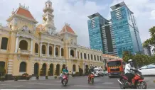  ?? AFP-Yonhap ?? Cars and motorcycli­sts ride past the City Hall, a French-colonial era building, with a nearby new shopping mall in the background in Ho Chi Minh City (former Saigon), Feb. 21. Saigon's colonial buildings are fast disappeari­ng.