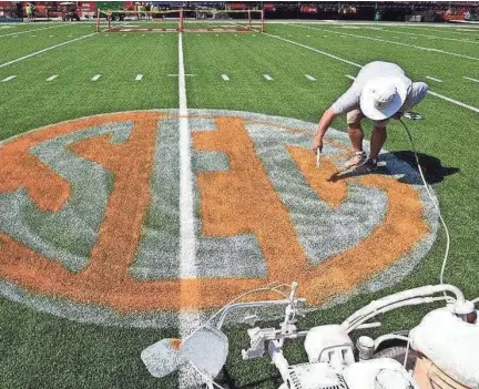  ?? MICHAEL PATRICK/NEWS SENTINEL ?? University of Tennessee field crew member Darren Seybold paints the SEC logo on the field Sept. 5, 2016 for The Battle At Bristol.