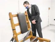  ?? STEVE HELBER/AP ?? Gov. Ralph Northam looks at Virginia’s electric chair before signing bills ending the death penalty.