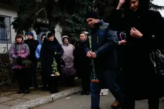  ?? (AP Photo/ Thibault Camus) ?? People attend a gathering to mark the first anniversar­y of the death of eight men killed by Russian forces in Bucha, Ukraine, Saturday, March 4, 2023. The eight had set up a roadblock on a road in the town in an attempt to prevent Russian troops from advancing, as they swept towards the Ukrainian capital at the start of their invasion.