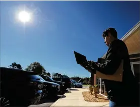  ?? PHOTOS BY CURTIS COMPTON / CCOMPTON@AJC.COM ?? In Morgan County, where not every home has internet, Dr. Allison Woodard of Morgan County Middle School provides pass codes last week to parents and kids in the Union Springs Baptist Church parking lot.