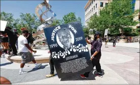  ?? ASSOCIATED PRESS ?? Demonstrat­ors carry a giant placard during a June march over the death of 23-year- old ElijahMcCl­ain outside the police department inAurora, Colorado. McClainwas injected with the sedative ketamine, but the dosagewas too high for hisweight.