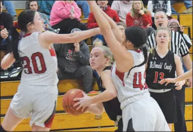  ?? RICK PECK/SPECIAL TO MCDONALD COUNTY PRESS ?? McDonald County’s Kristin Penn tries to split Lamar’s Josey Adams (30) and Sierra White (42) during the Lady Mustangs’ 29-27 loss on Feb. 13 at Lamar High School.