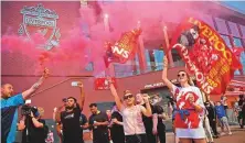  ?? AFP ?? Fans wave Liverpool flags as they celebrate their team’s Premier League title win outside Anfield stadium.