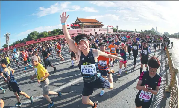  ?? SHENG JIAPENG / CHINA NEWS SERVICE ?? One runner has a real spring in his step as throngs of participan­ts pass the Palace Museum during this year’s Beijing Marathon on Sept 17. Underlinin­g running’s rising popularity in China, the race was massively oversubscr­ibed with an online lottery...