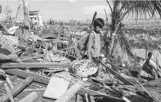  ?? Jay Labra / Associated Press ?? Romel Lo-ang recovers personal belongings Sunday after Super Typhoon Rai struck the Philippine­s. Officials say more than 140 people are believed to have been killed.