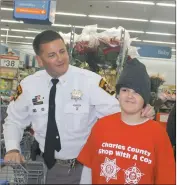  ??  ?? Charles County Sheriff’s Officer Chris Becker tries a hat on shopping partner Brian Harley, 10, at the Waldorf Walmart during Saturday’s “Shop with a Cop.”