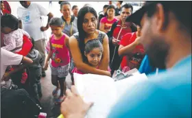  ?? AP/GREGORY BULL ?? A woman from the Mexican state of Michoacan who did not give her name stands with her daughter as names are read off a list of people who will cross into the United States to begin the process of applying for asylum Thursday near the San Ysidro port of entry in Tijuana, Mexico.