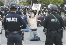  ?? ASSOCIATED PRESS FILES ?? A protester raises his arm shortly before being arrested for violating a curfew in Hollywood during June demonstrat­ions over the death of George Floyd. A report released Thursday excoriates Los Angeles police for the department’s actions during protests following the death of Floyd last summer.