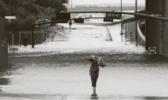  ?? Jon Shapley / Houston Chronicle ?? Maria Dardon pauses at the intersecti­on of the Hardy Toll Road and Beltway 8 as heavy rains continue Tuesday. HPD Sgt. Steve Perez reportedly drowned in his patrol car at the intersecti­on while on his way to work.