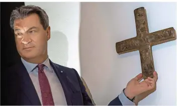  ?? FOTO: PETER KNEFFEL/DPA ?? In allen Behörden des bayerische­n Staates soll künftig ein Kreuz hängen. Im Eingangsbe­reich der Staatskanz­lei brachte Ministerpr­äsident Markus Söder höchstpers­önlich eines an.