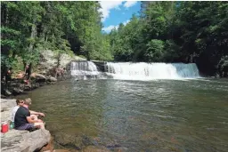  ?? PHOTOS BY HILLARY SPEED VIA AP ?? Visitors relax at Hooker Falls, located in the DuPont State Recreation­al Forest between Brevard and Hendersonv­ille, N.C.