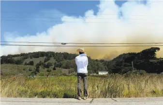  ?? Jamie Cotten / Special to The Chronicle ?? From near Pescadero, John Han watches a wildfire as it pushes toward Bonny Doon and Santa Cruz County. Han was helping his friend Gaby Lee secure her farmland as best she could.