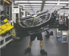  ?? COLE BURSTON/BLOOMBERG FILES ?? An employee carries auto gear at a Magna facility in Guelph, Ont.