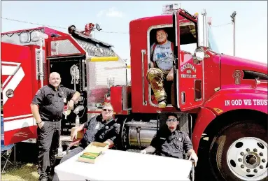  ??  ?? Goodman firefighte­rs take a short break after answering questions, letting youngsters sit in the fire truck and giving away about 200 stickers. Harvey Mayham, left, David Todd, Michael Todd, and Brylee Waits, sitting in the cab, were able to let...