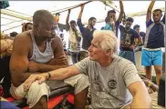  ?? VALERIO NICOLOSI / AP ?? Actor Richard Gere (right) talks with migrants Friday aboard the Open Arms, a Spanish humanitari­an boat, as it cruises in the Mediterran­ean Sea. Open Arms has been carrying 121 migrants for a week in the Mediterran­ean awaiting a safe port to dock.