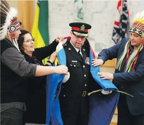  ?? MICHELLE BERG ?? New Saskatoon police Chief Troy Cooper is wrapped in a blanket by Muskeg Lake Chief Kelly Wolfe, FSIN vice-chief Kim Jonathan and Saskatoon Tribal Council Chief Mark Arcand after being officially sworn in at the city council chambers on Wednesday.