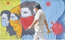  ?? INDRANIL MUKHERJEE/AGENCE FRANCE-PRESSE ?? WITHOUT even glancing, a pedestrian walks past a wall mural representi­ng awareness measures against the coronaviru­s in Navi, Mumbai.