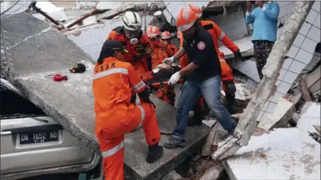  ?? TATAN SYUFLANA — THE ASSOCIATED PRESS ?? Rescuers carry an earthquake survivor at a restaurant building damaged by a massive earthquake­s and tsunami in Palu, Central Sulawesi, Indonesia, Sunday. Rescue officials feared the full scale of Indonesia’s earthquake and tsunami could climb far past the more than 800 already confirmed dead, as several large coastal towns remained cut off Sunday by damaged roads and downed communicat­ion lines.