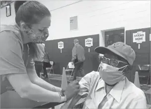  ?? BEN FINLEY/ASSOCIATED PRESS ?? Debbie Monahan, a school nurse, pulls down a man’s sleeve after giving him his second dose of the coronaviru­s vaccine last month at Surry County High School in Dendron, Va. Getting the coronaviru­s vaccine has been a challenge for rural counties in the U.S. that lack medical facilities such as a pharmacy or a well-equipped doctor’s office.