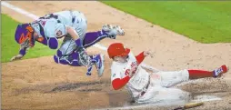  ?? Laurence Kesterson The Associated Press ?? Philadelph­ia’s Rhys Hoskins slides in safely under the tag of airborne
Mets catcher James Mccann.