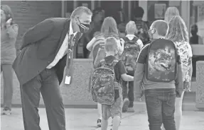  ?? GREG WOHLFORD/USA TODAY NETWORK ?? Union City Area School District Superinten­dent Matt Bennett, left, greets elementary students on Aug. 25, the first day of school, in Union City, Pa. Staff, students and parents are adjusting to a new routine during the COVID-19 pandemic.