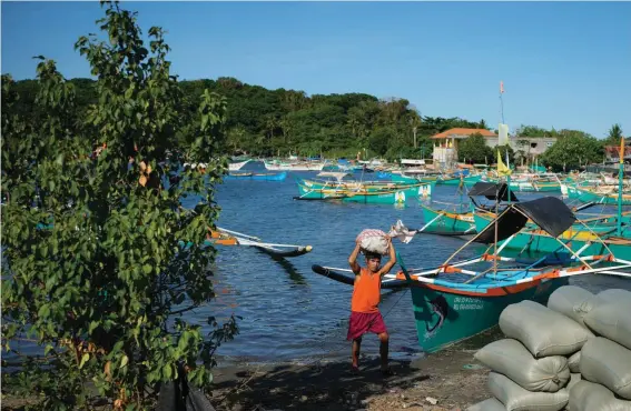  ?? ?? A resident brings down a sack from his boat at the coastal town of Santa Ana, Cagayan province, northern Philippine­s on Tuesday, May 7, 2024. The United States and the Philippine­s, which are longtime treaty allies, have identified the far-flung coastal town of Santa Ana in the northeaste­rn tip of the Philippine mainland as one of nine mostly rural areas where rotating batches of American forces could encamp indefinite­ly and store their weapons and equipment within local military bases under the Enhanced Defense Cooperatio­n Agreement, or EDCA. (AP Photo/Aaron Favila)