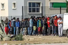  ??  ?? Charity: A queue of migrants waiting at a food van in Calais