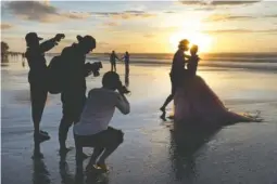  ?? FILE PHOTO BY FIRDIA LISNAWATI/ THE ASSOCIATED PRESS ?? Photograph­ers take pictures of a tourist couple’s wedding at the famous Kuta beach during sunset in Bali, Indonesia.