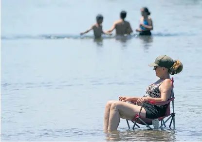  ?? ?? Angesichts der hohen Temperatur­en hat sich diese Frau in der kalifornis­chen Hauptstadt Sacramento dazu entschiede­n, ihren Campingstu­hl im American River zu positionie­ren, um ihre Beine zu kühlen.