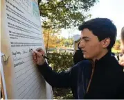  ?? Jerry Baker ?? Pablo Flower, a John Cooper School sophomore and current Director of the Human Rights Walk, signs the Petition to Implement the Unviversal Declaratio­n of Human Rights during the 7th Annual Human Rights Walk and Festival and Human Rights Day Celebratio­n...