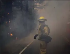  ?? JAE C. HONG — THE ASSOCIATED PRESS ?? A firefighte­r gestures to his colleagues as he walks through thick smoke from a wildfire Thursday near Calistoga, Calif.