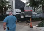  ??  ?? A medical worker walks past a refrigerat­ed trailer parked outside the Cedars- Sinai Medical Center in Los Angeles. California health authoritie­s reported Thursday 583 new deaths and a record two- day total of 1,042.