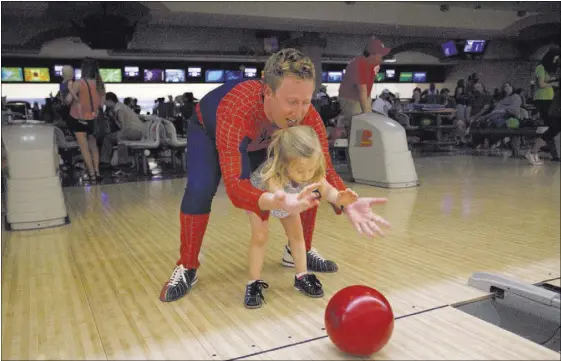  ?? LOREN TOWNSLEY/LAS VEGAS REVIEW-JOURNAL FOLLOW @LORENTOWNS­LEY ?? John Mac, of Sunny 106.5, teaches his daughter, Charlotte, how to bowl at the Homeless Youth in the Alley bowling tournament fundraiser Saturday at the Suncoast Bowling Center.