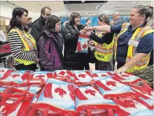  ?? NATHAN DENETTE THE CANADIAN PRESS ?? Newly arrived Syrian refugee Anjilik Jaghlassia­n, centre, and her family receive winter clothes and other items at Toronto’s Pearson Internatio­nal airport in December 2015.