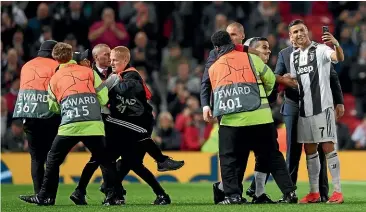  ??  ?? Juventus star Cristiano Ronaldo takes a selfie with two fans who had invaded the pitch during the Champions League match against Manchester United at Old Trafford. GETTY IMAGES