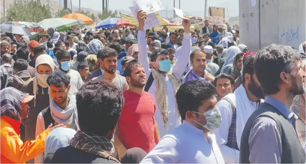  ?? STRINGER / REUTERS ?? Crowds of people show their documents to U.S. troops outside the airport in Kabul on Thursday as they try to leave the country.